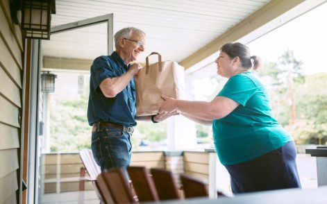 Homebound Friends Man Receiving Groceries from Volunteer.